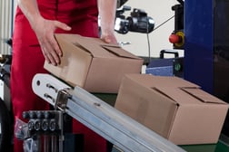 Close-up of worker putting a box on conveyor belt for shipping, manufacturing warehouse automation 